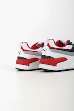 Two athletic shoes with bold red, white, and dark blue color blocking. The shoes feature a sleek, modern design with a flat sole and a recognizable logo in black on the heel. The upper part is made of a mix of textiles with some parts having perforations for breathability.