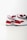 Two athletic shoes with bold red, white, and dark blue color blocking. The shoes feature a sleek, modern design with a flat sole and a recognizable logo in black on the heel. The upper part is made of a mix of textiles with some parts having perforations for breathability.