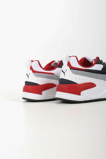 Two athletic shoes with bold red, white, and dark blue color blocking. The shoes feature a sleek, modern design with a flat sole and a recognizable logo in black on the heel. The upper part is made of a mix of textiles with some parts having perforations for breathability.