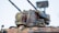 A detailed model of a military tank featuring a camouflage pattern and various mounted components, including antennas and a radar system. The tank is adorned with a distinct emblem on its turret.