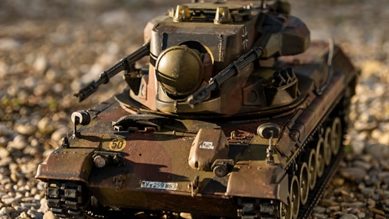 Close-up of a detailed military vehicle model being painted with fine brushes and precision tools.