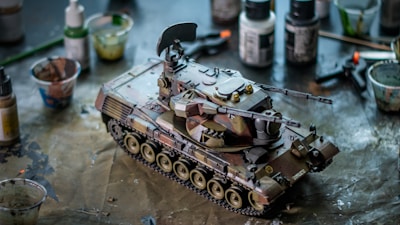 Detailed tank model kit with camouflage paint on a workbench.
