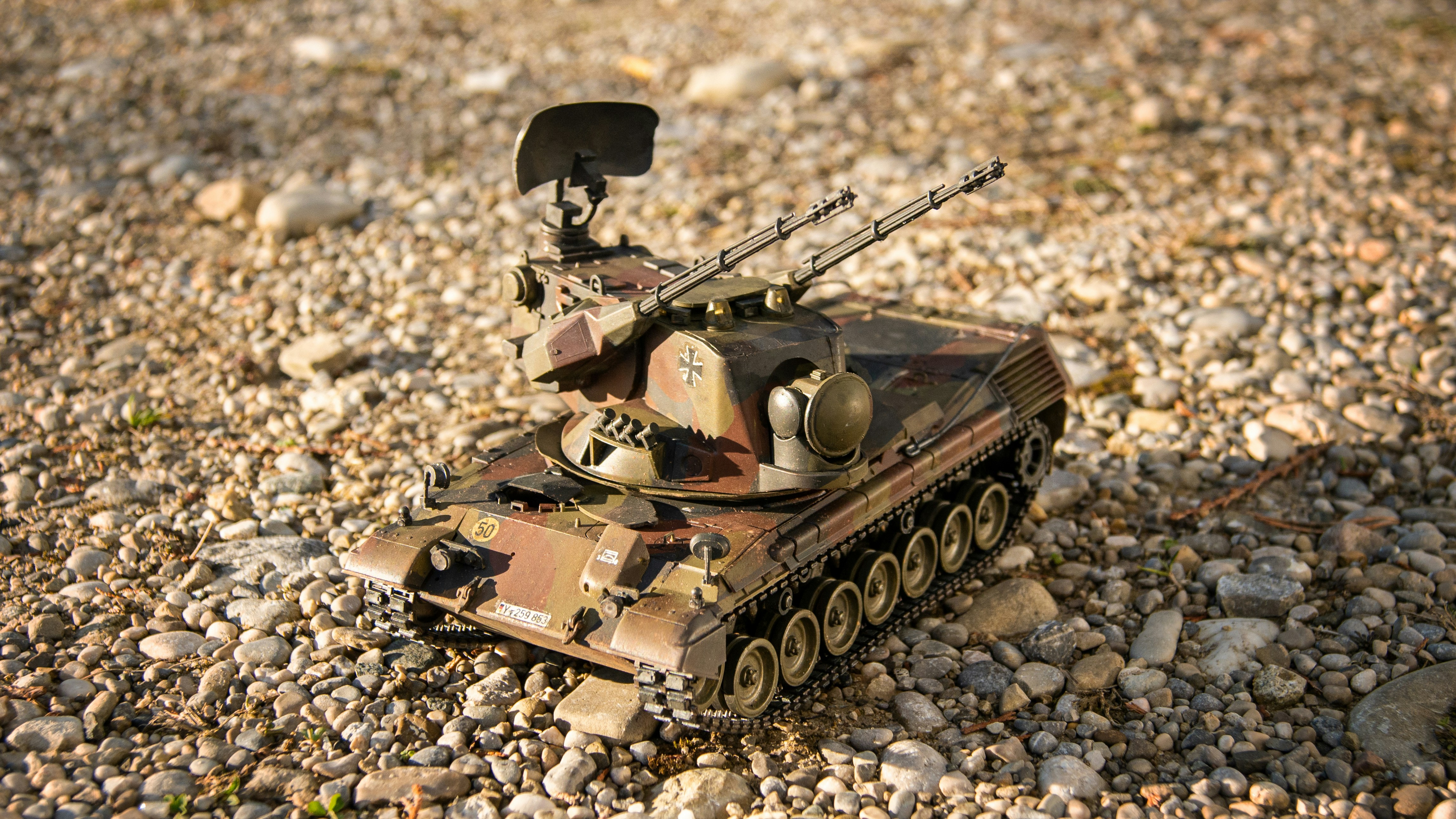 a toy tank sitting on top of a gravel field