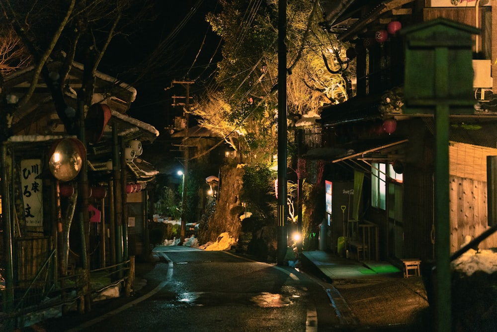 a street at night with a clock on the side of it