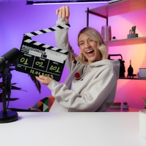 a woman holding a clapper in front of a camera