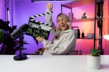 a woman holding a clapper in front of a camera