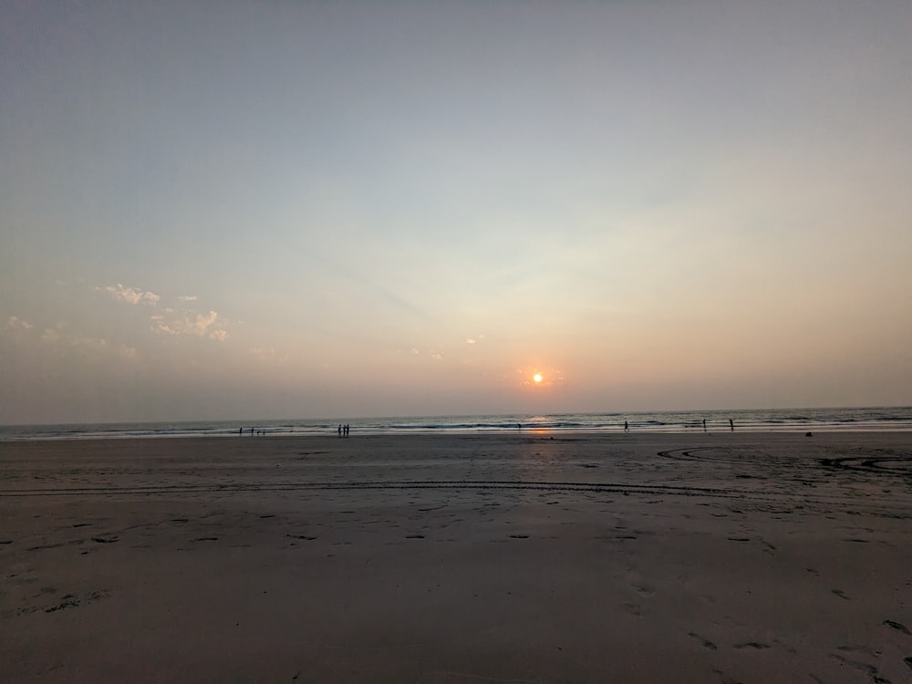 the sun is setting over the ocean on the beach