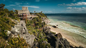 a group of people standing on top of a cliff next to the ocean