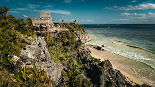 a group of people standing on top of a cliff next to the ocean