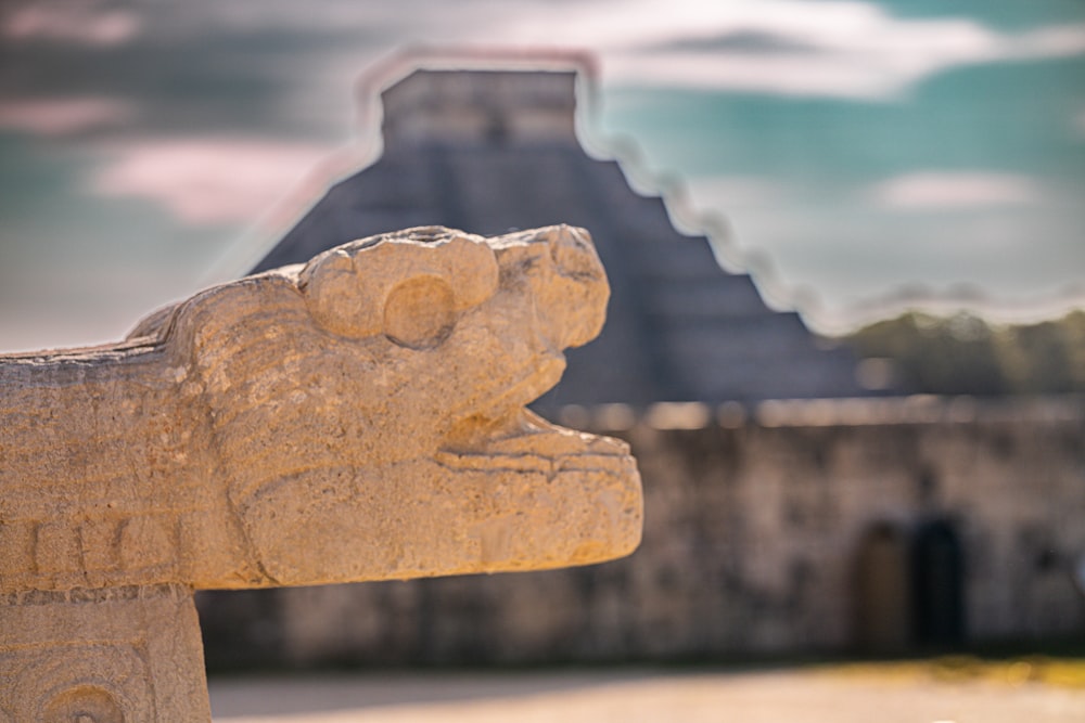 a statue of a gargoyle in front of a pyramid