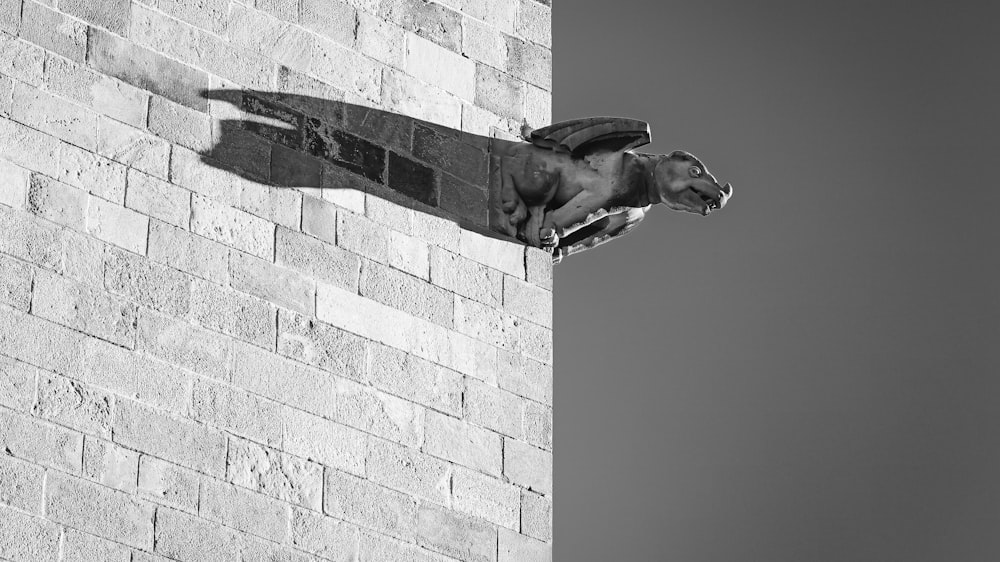 a black and white photo of a gargoyle on a brick wall