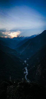 A serene mountain landscape at dawn with soft golden light illuminating a winding river.
