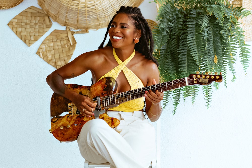 a woman in a yellow shirt is playing a guitar