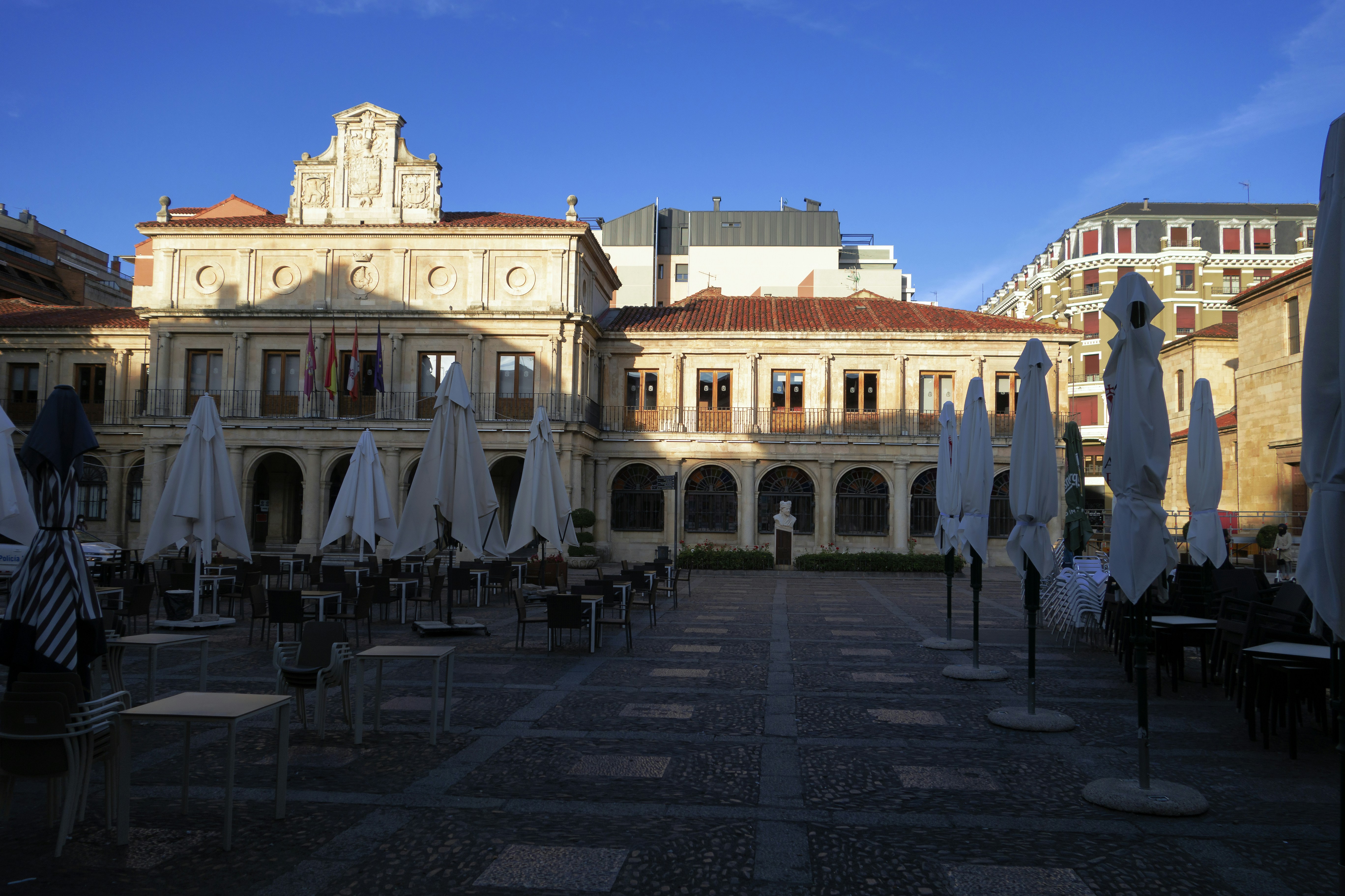 a courtyard with tables and umbrellas in front of a building