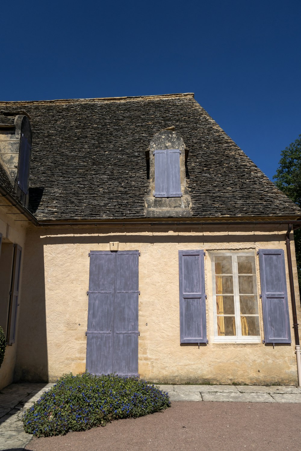 uma casa com persianas azuis e um telhado marrom