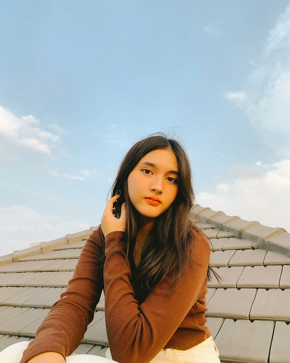 a woman sitting on a roof talking on a cell phone