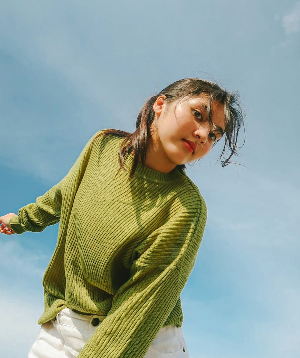 a woman in a green sweater and white shorts