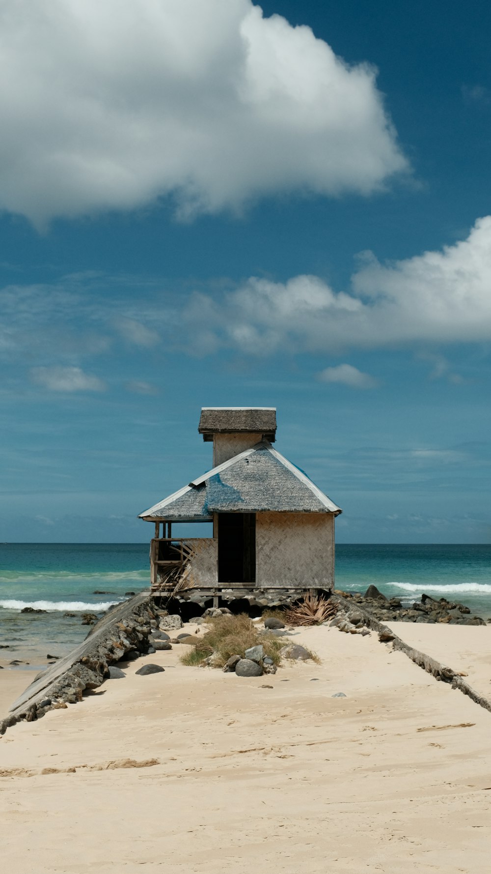a small hut on a beach with the ocean in the background