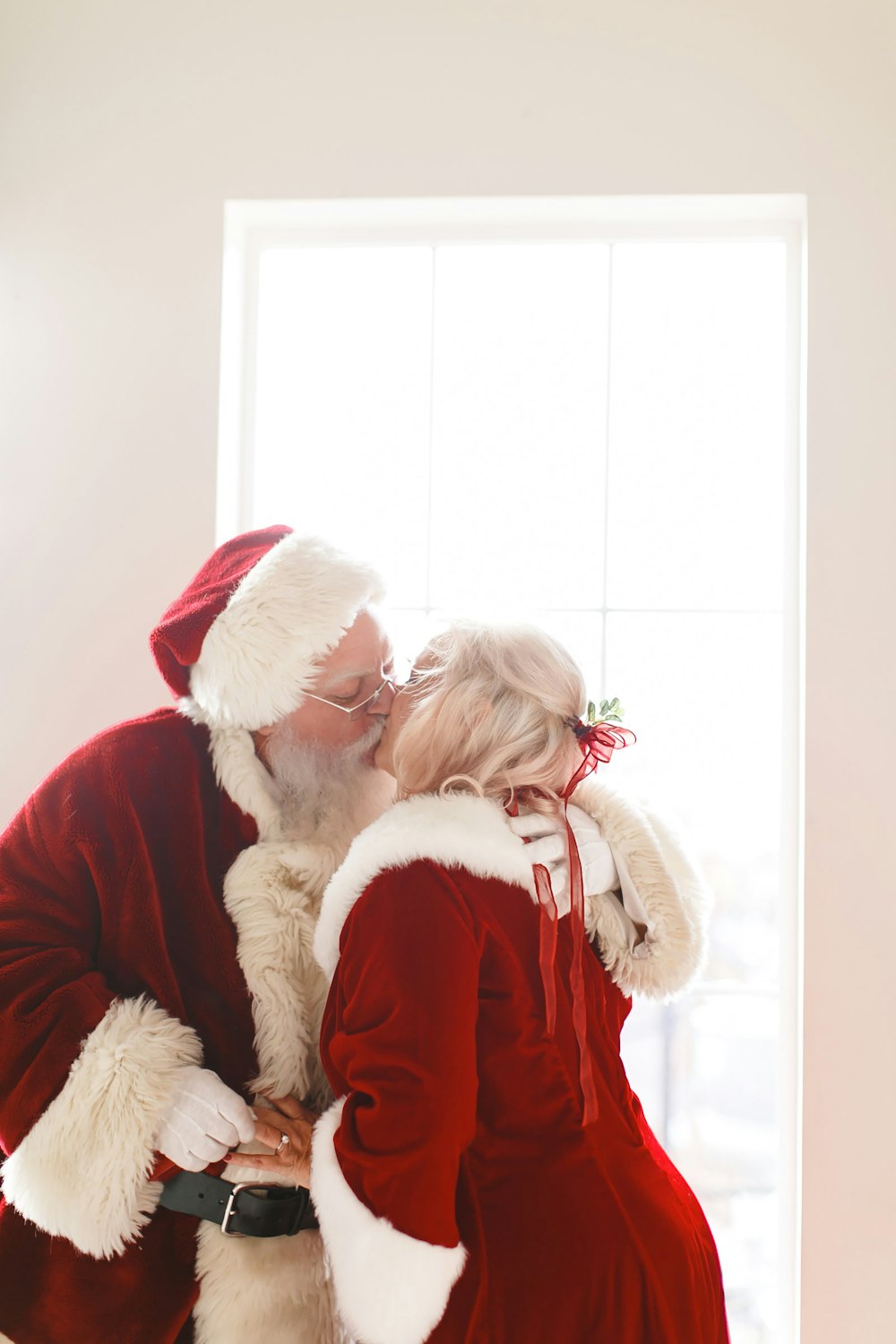 a man in a santa suit kissing a little girl