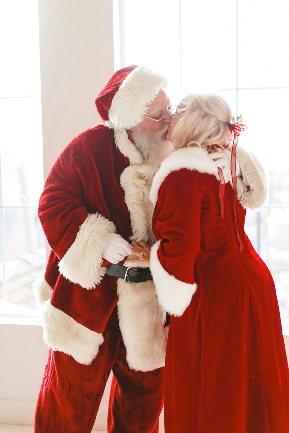 a man in a santa suit kissing a woman in a red dress