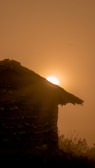 Sunset casting warm light over a rustic stone house perched on a quiet Sicilian hillside.