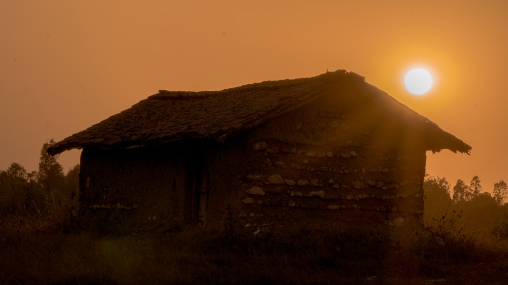 Die Sonne geht hinter einer kleinen Hütte unter