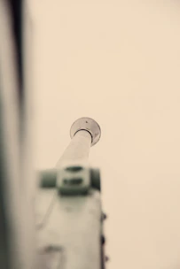 Close-up of a sleek telescopic pole extending smoothly against a deep blue background.