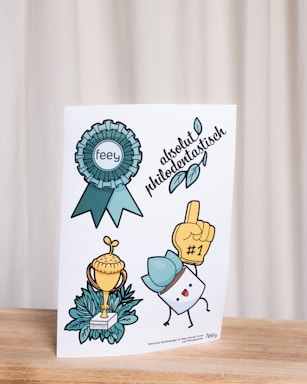 A set of colorful illustrations on a card, including a blue rosette with the word 'feey', a trophy with leaves at the base, a cartoon character with a blue hat holding a '#1' foam finger, and the phrase 'absolut philodentastisch' with decorative leaves.
