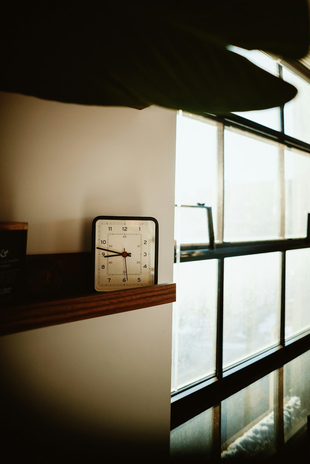 a clock sitting on top of a shelf next to a window