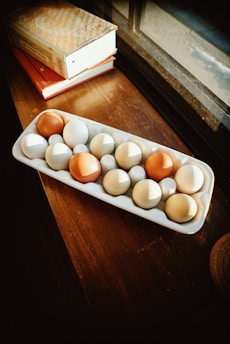 A variety of fresh eggs displayed in natural light on a wooden table.