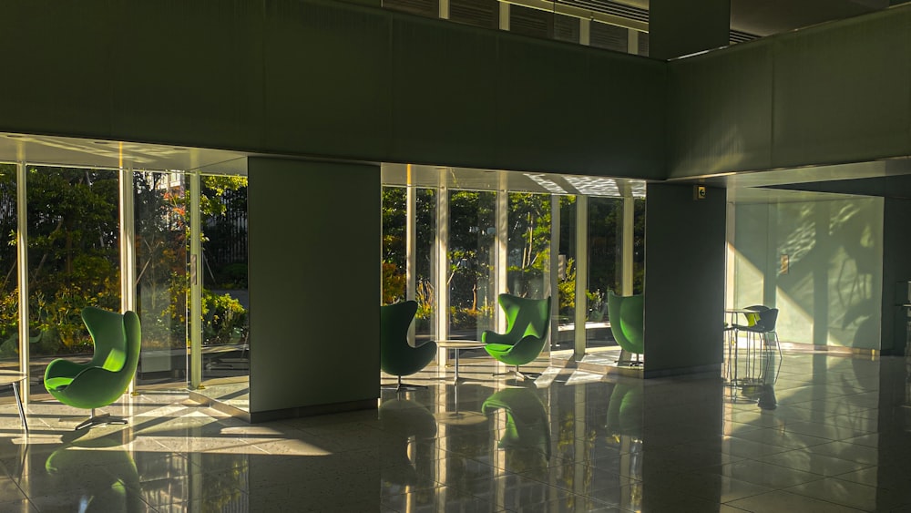 a room filled with lots of windows and green chairs