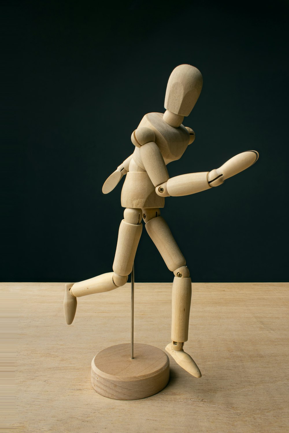 a wooden mannequin standing on a wooden base