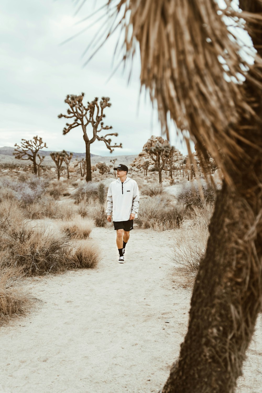 a man walking down a dirt road in the desert