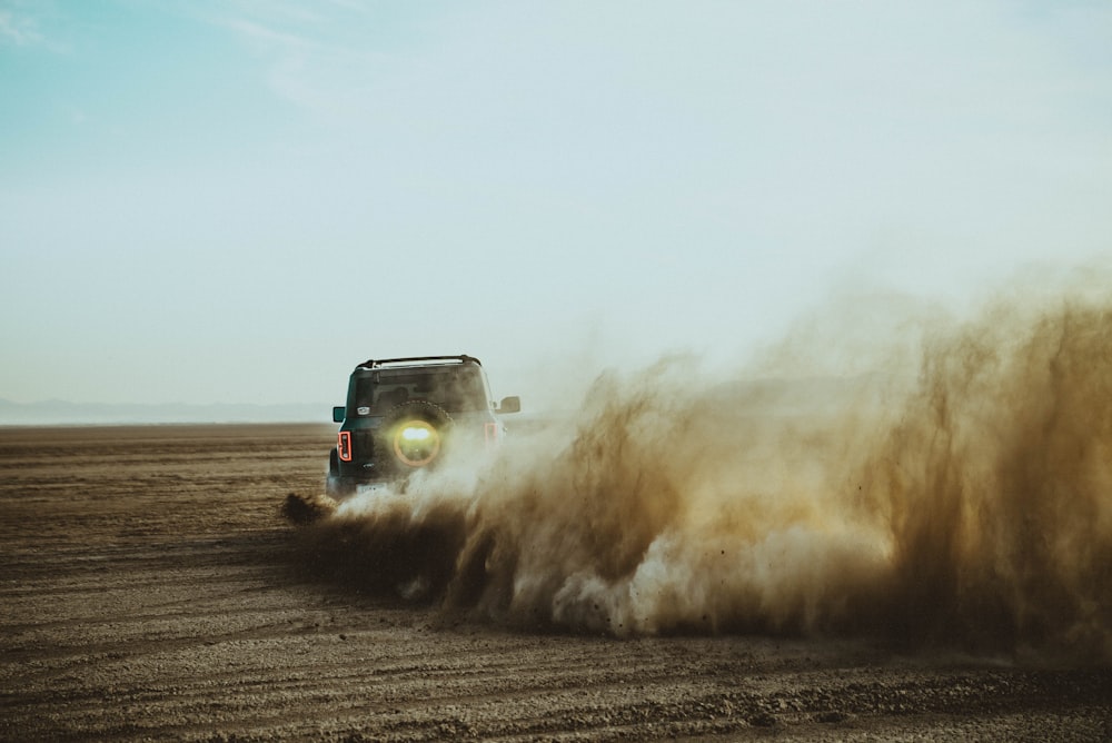 a jeep driving through a field of dirt