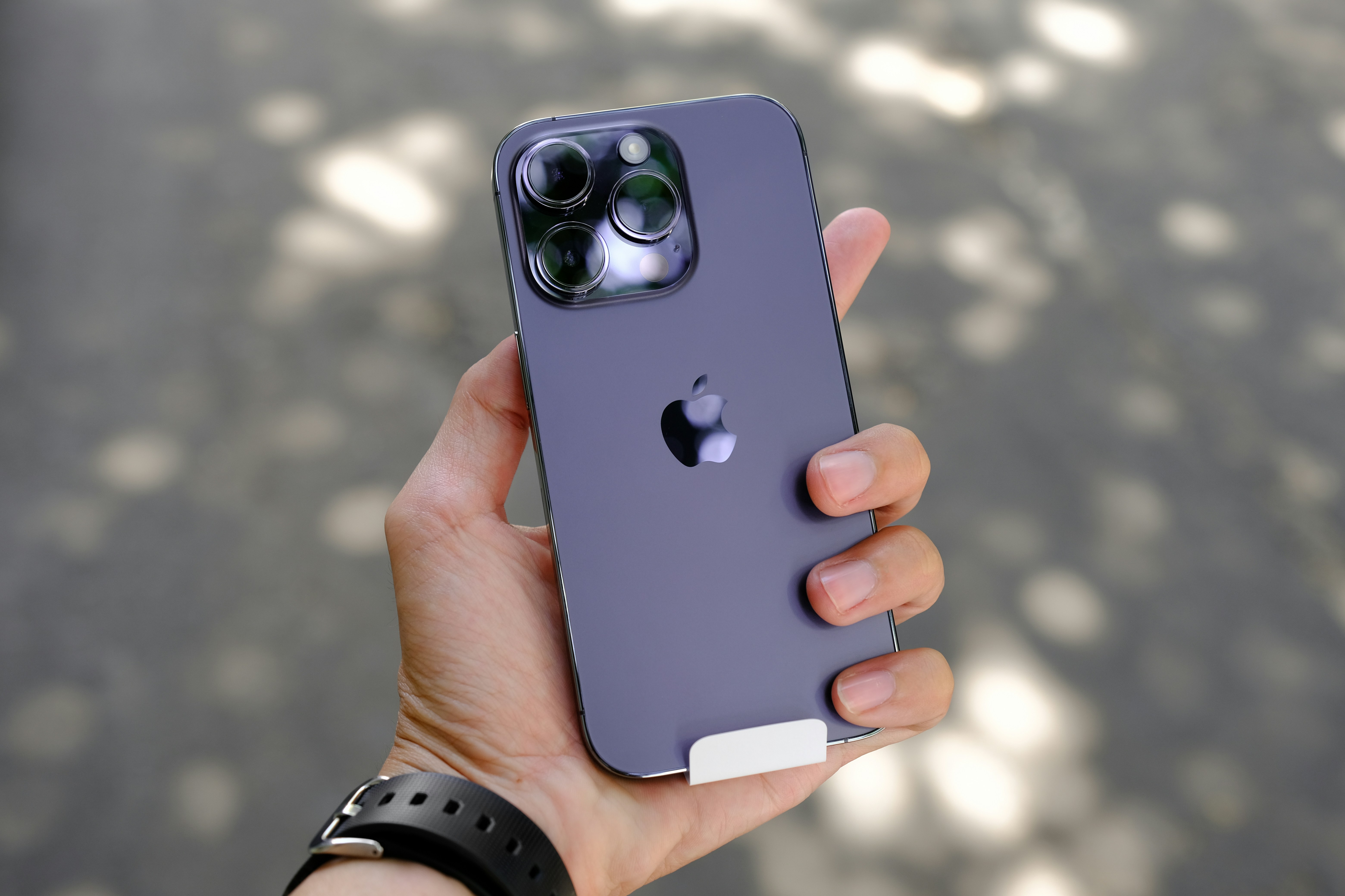 iPhone 14 in deep purple held in hand outdoors