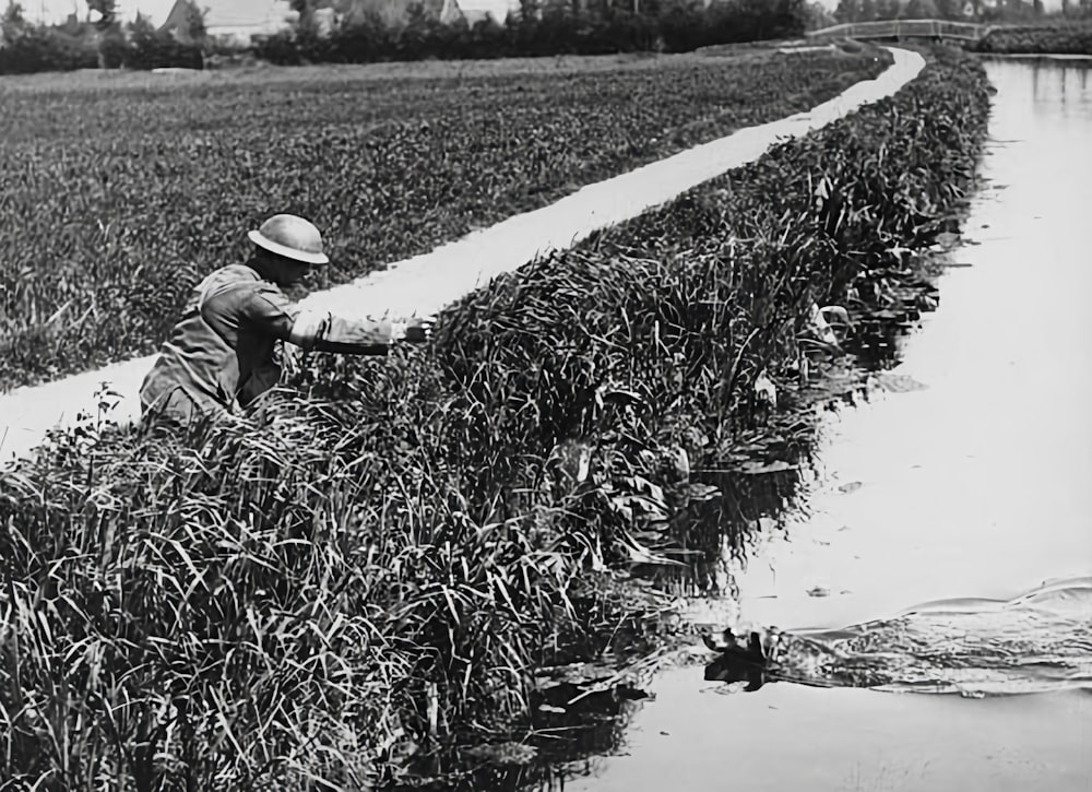 a man kneeling down next to a body of water