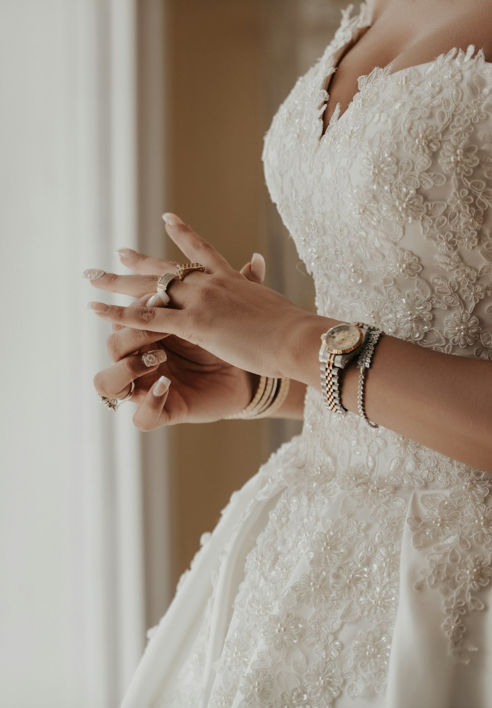a woman in a wedding dress putting on her wedding ring