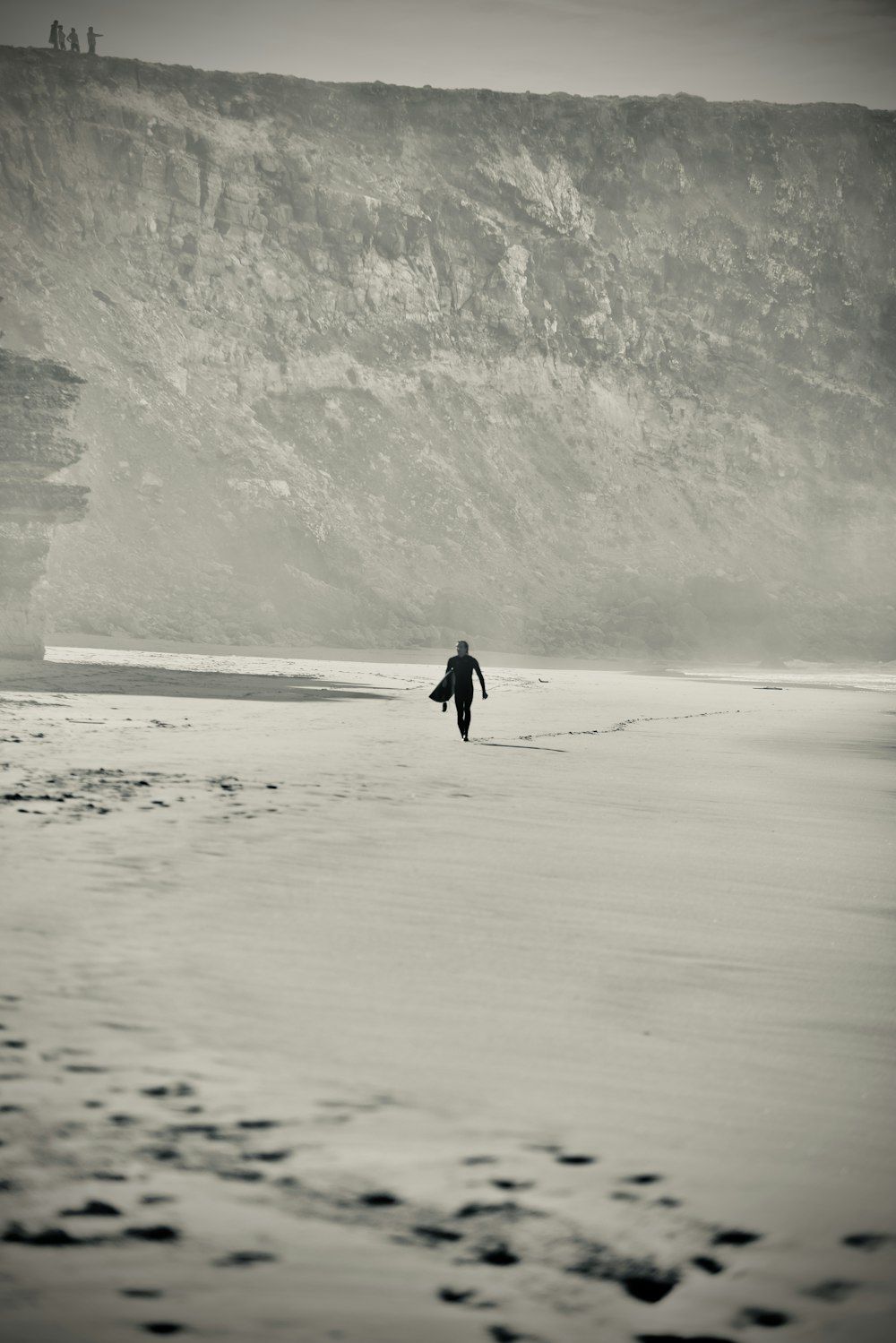 a person walking on a beach near a mountain