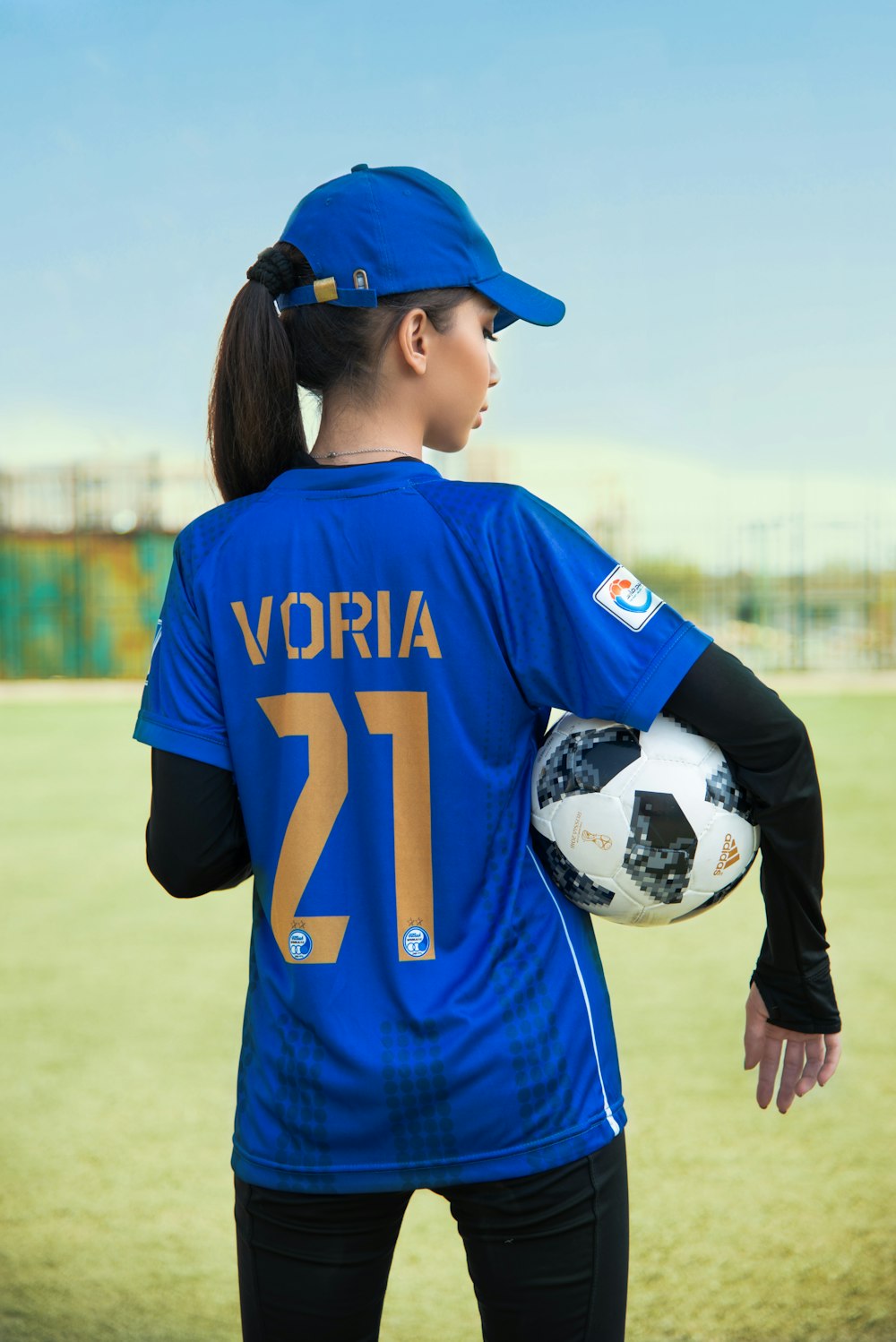 a woman in a blue uniform holding a soccer ball