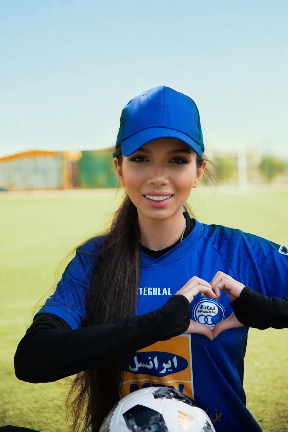 a woman holding a soccer ball on top of a field