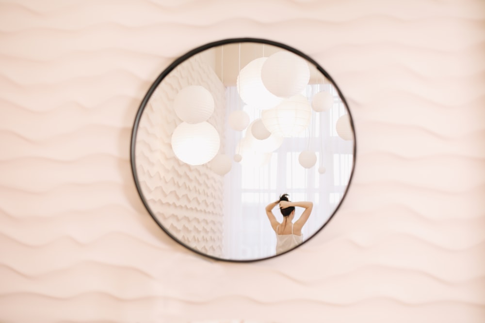 a woman standing in front of a round mirror