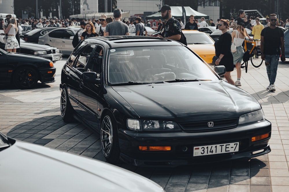a black car parked in front of a crowd of people