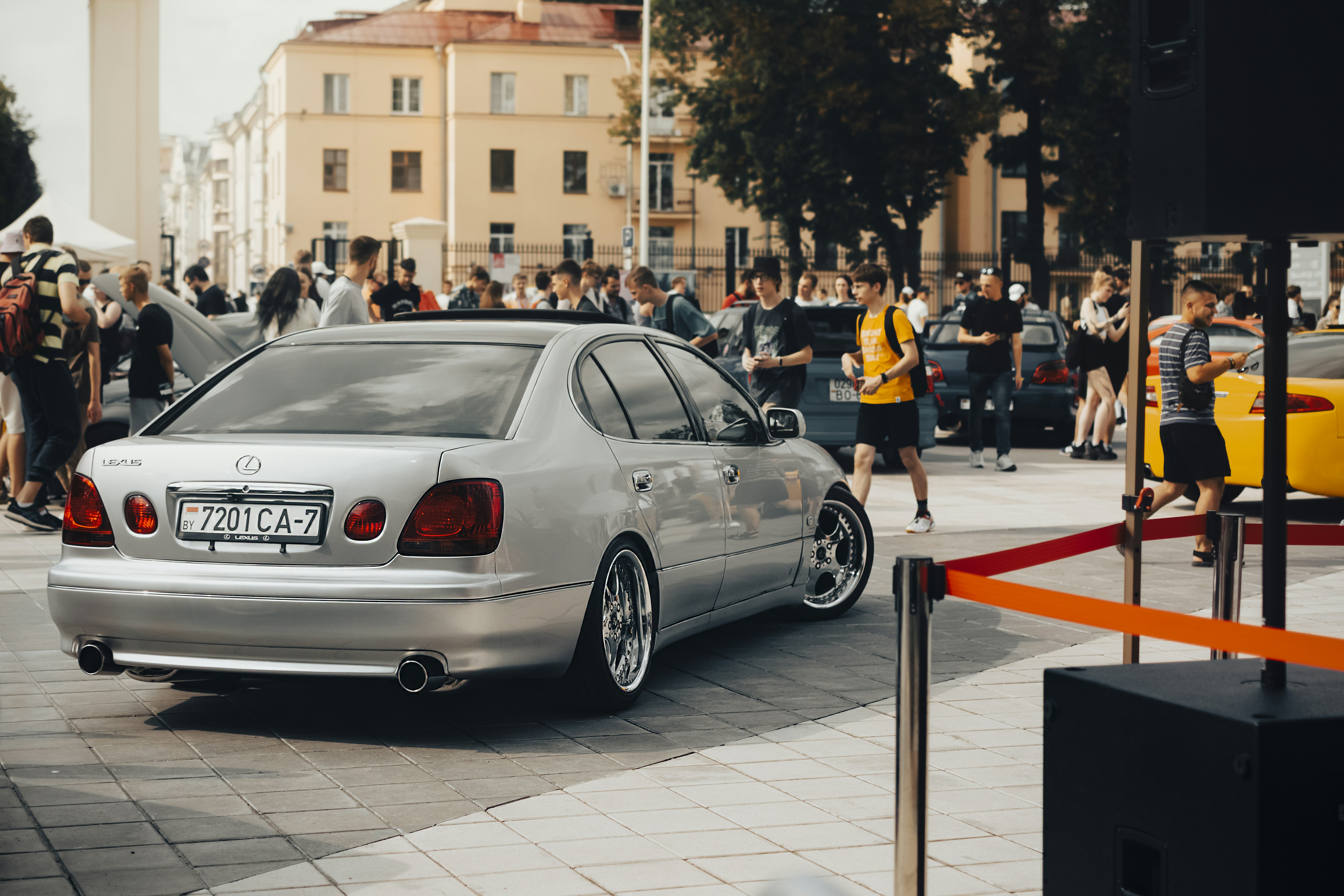 Ein silbernes Auto parkt vor einer Menschenmenge