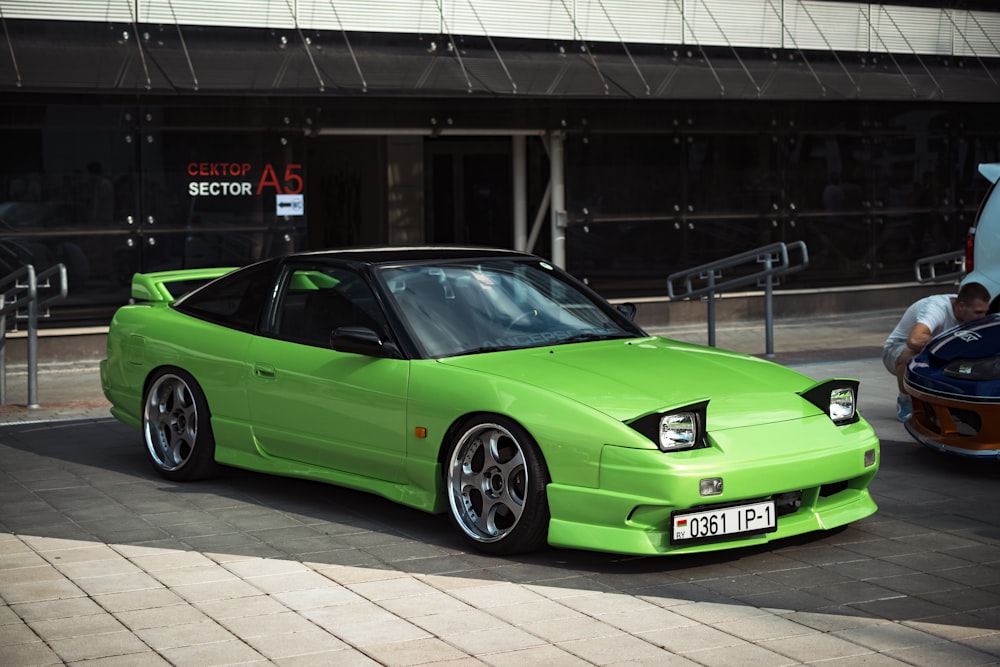 a green sports car parked in front of a building