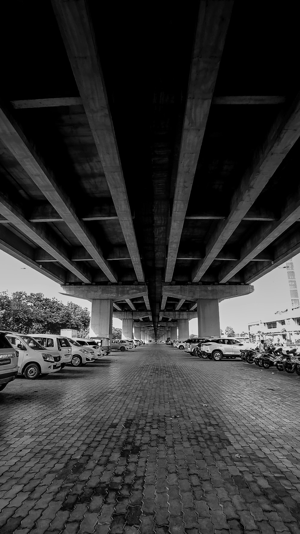 a black and white photo of cars parked under a bridge