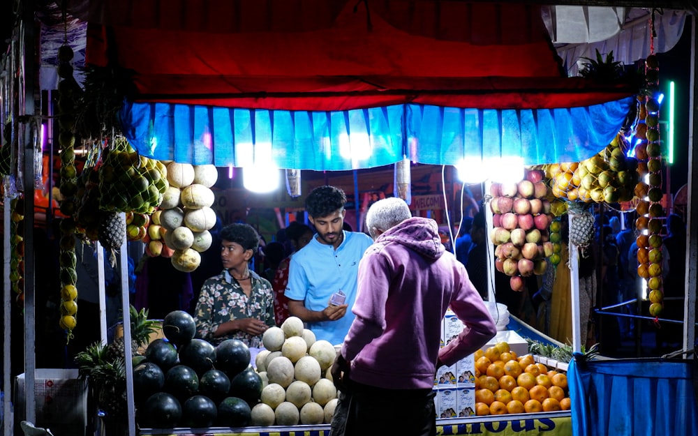 a group of people standing around a fruit stand