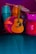 A collection of musical instruments including a teal conga, a vibrant orange djembe, a wooden acoustic guitar, and a large pink drum, all set against a deep purple background. The instruments are arranged closely together, showcasing a variety of textures and materials.