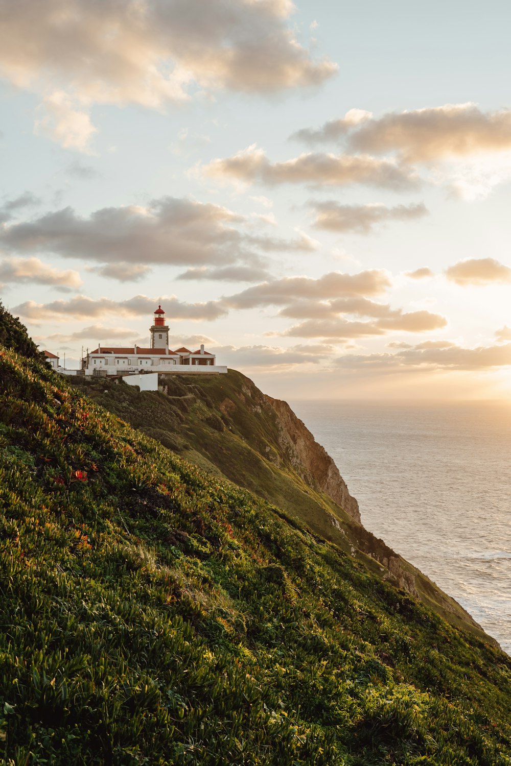 a lighthouse on top of a hill near the ocean