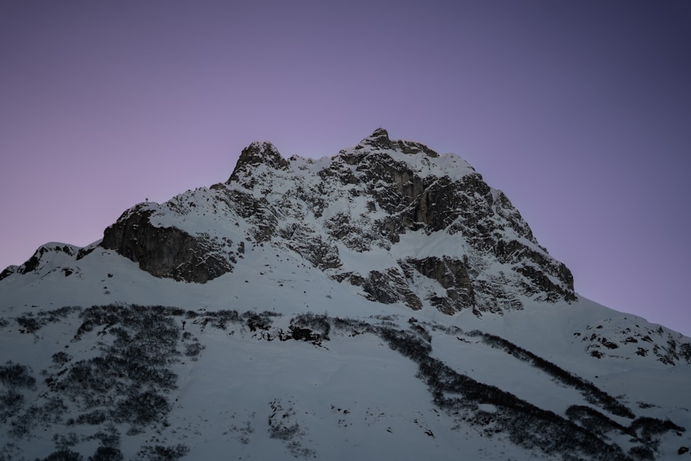 a very tall mountain covered in snow under a purple sky