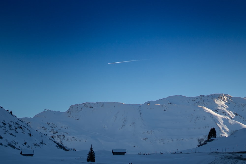 Una montagna coperta di neve con un aereo che vola nel cielo